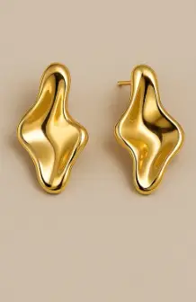 Pendientes Onda Dorada Par de pendientes stud esculturales de color dorado intenso con un diseño orgánico y fluido. La forma es asimétrica y abultada, similar a metal líquido o una gota, con un acabado pulido de alto brillo sobre un fondo beige claro.